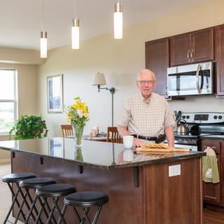 A man stands in a modern kitchen with a large countertop, decorated with flowers.