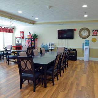 A spacious dining area with a large table and several chairs, featuring a television and modern interior decor.