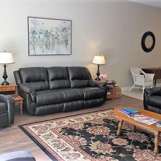 A cozy living room with black leather sofas, a patterned rug, and elegant lighting.
