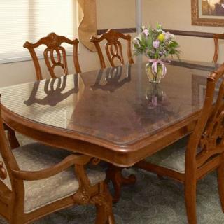 A polished wooden dining table set with ornate chairs and a vase of flowers.