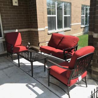Outdoor patio set with red cushioned chairs and a table.