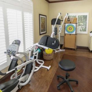 A home gym setup featuring various exercise equipment and a wall target for practice.