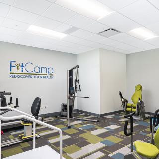 A modern fitness center equipped with various exercise machines and a colorful floor design.