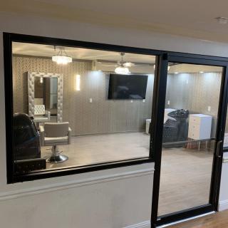 A modern beauty salon interior featuring a styling station with a mirror, chair, TV, and sleek lighting.