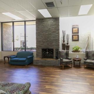 A modern lobby with comfortable seating and a fireplace, featuring ample natural light from large windows.