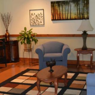 A cozy living room with blue armchairs, a patterned rug, and decorative artwork.