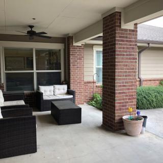 A cozy outdoor patio with comfortable seating, potted plants, and a ceiling fan.