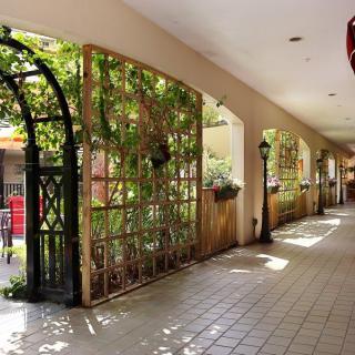 A sunlit arched walkway adorned with lattice and greenery.