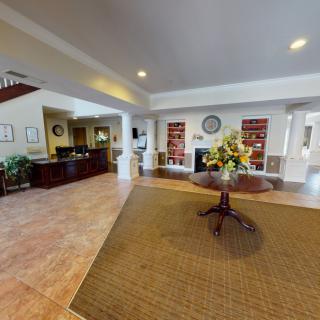 A spacious and welcoming lobby area with a reception desk, bookshelves, and a central table adorned with a floral arrangement.