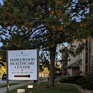 The sign for Maplewood Healthcare Center, surrounded by trees and a clear blue sky.
