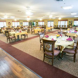 A well-organized dining hall with neatly arranged tables and chairs, featuring warm lighting and elegant decor.