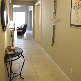 A well-lit hallway with wall decorations and a small side table, leading to a living area.