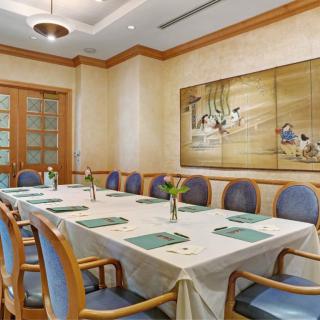 A well-appointed conference room with a long meeting table, surrounded by cushioned chairs and adorned with wall art.