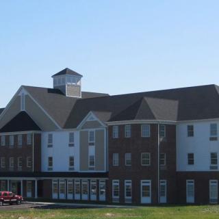 A large hotel building with a mix of brick and white-paneled exterior under a clear blue sky.