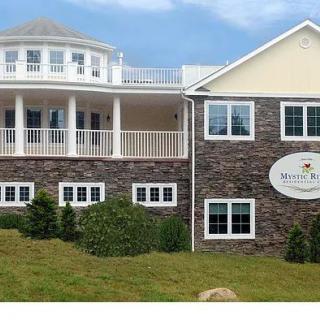 A two-story building with a stone facade and a balcony, featuring signage on the front.
