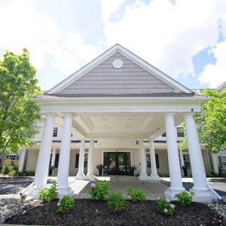 A stately building entrance with large white columns and manicured landscaping.