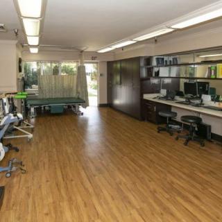 Interior of a medical clinic with workstations and examination tables.