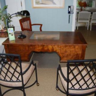 A neatly arranged office desk with two chairs in front and a lamp on the side.
