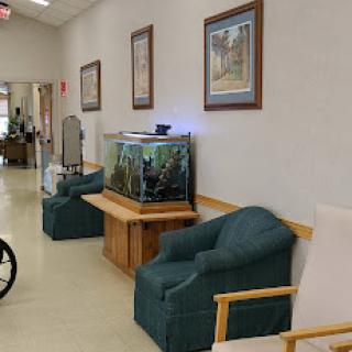 A calm waiting area in a hospital featuring comfortable chairs, a fish tank, and wall art.
