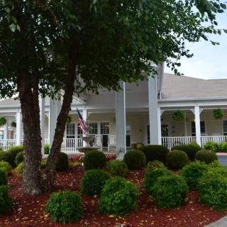 A front view of a building with a landscaped garden featuring trees and bushes.