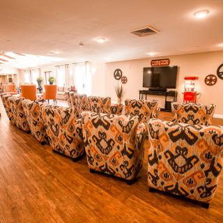 A cozy lounge area with patterned chairs facing a TV for group entertainment.