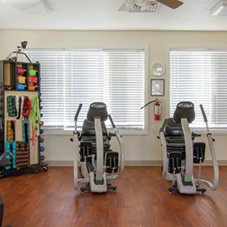 A fitness room with exercise machines and therapy supplies.