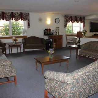 A cozy living room with multiple sofas, tables, and windows letting in natural light.