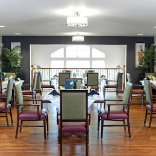 A spacious and well-lit dining room featuring comfortable chairs and a warm wooden floor.