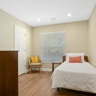 A minimalist bedroom with a single bed and wooden flooring.