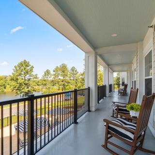 A spacious porch with rocking chairs overlooking a scenic view of trees and a clear sky.