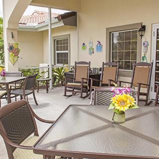 A cozy outdoor patio area with tables, chairs, and decorative flowers.