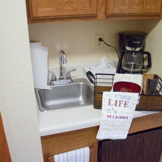 A small kitchen area with a sink, coffee maker, and other essentials.