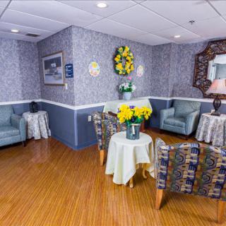 A cozy waiting area with comfortable chairs, a table adorned with flowers, and decorative elements on the walls.