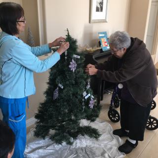 Two people decorating a Christmas tree indoors.