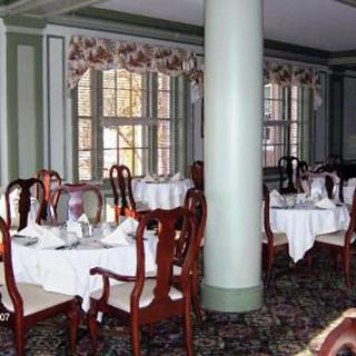 An elegant restaurant dining room with neatly set tables and classic wooden chairs.