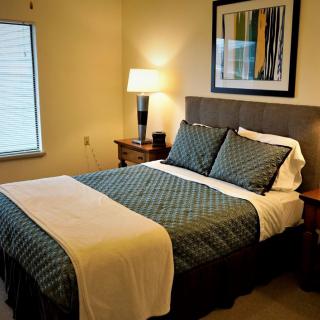 A cozy bedroom with a neatly made bed, bedside tables, and a warm lamp.