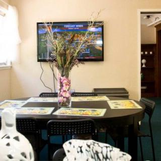 A dining room setup with a table centerpiece and a television mounted on the wall.