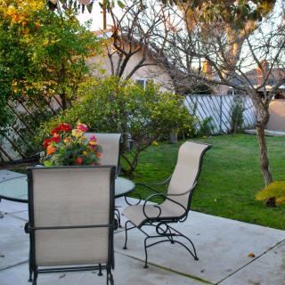 A tranquil patio with a table and chairs surrounded by lush greenery.