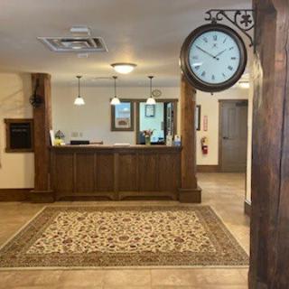 A hotel lobby with a reception desk, ornate rug, and a wall-mounted clock.