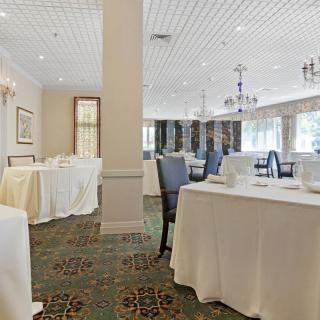 An elegant banquet hall with white tablecloths and chandeliers, set up for an event.