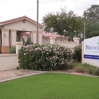 A residential building with a sign and landscaped garden in front.