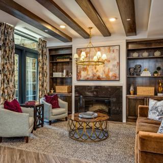 A cozy and elegantly decorated living room featuring a fireplace, comfortable seating, and modern artwork.