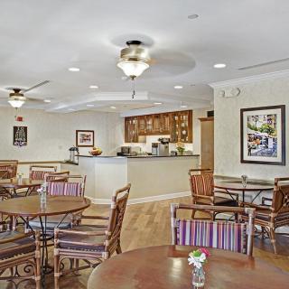 A cozy dining area with tables and chairs, featuring ceiling fans and warm lighting.