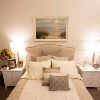 A cozy bedroom with a neatly made bed, flanked by two nightstands and lamps, featuring artwork above the headboard.