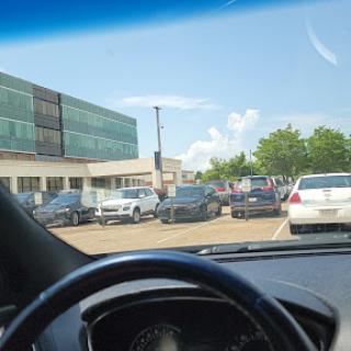 A view of a busy parking lot with various cars parked outside a modern building.