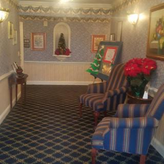A cozy hotel hallway with striped chairs, decorative plants, and framed artwork on the walls.