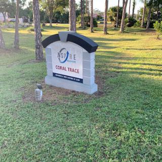A prominently displayed sign marking the location of Coral Trails, surrounded by greenery.
