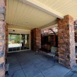 An inviting outdoor entrance with stone pillars and a shaded seating area.