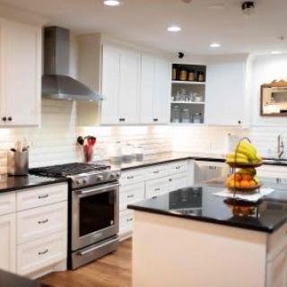 Modern kitchen with white cabinets and black countertops featuring a central island and stainless steel appliances.