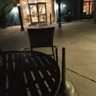 A quiet outdoor seating area at night, featuring empty chairs and a table.